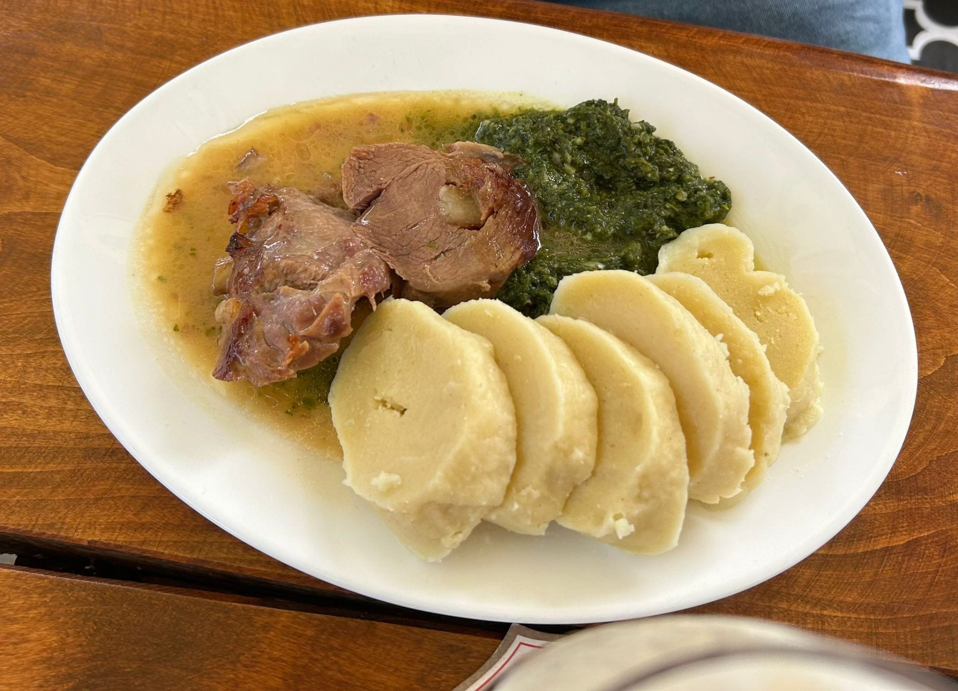 Maso s houskovými knedlíky a špenátem na talíři