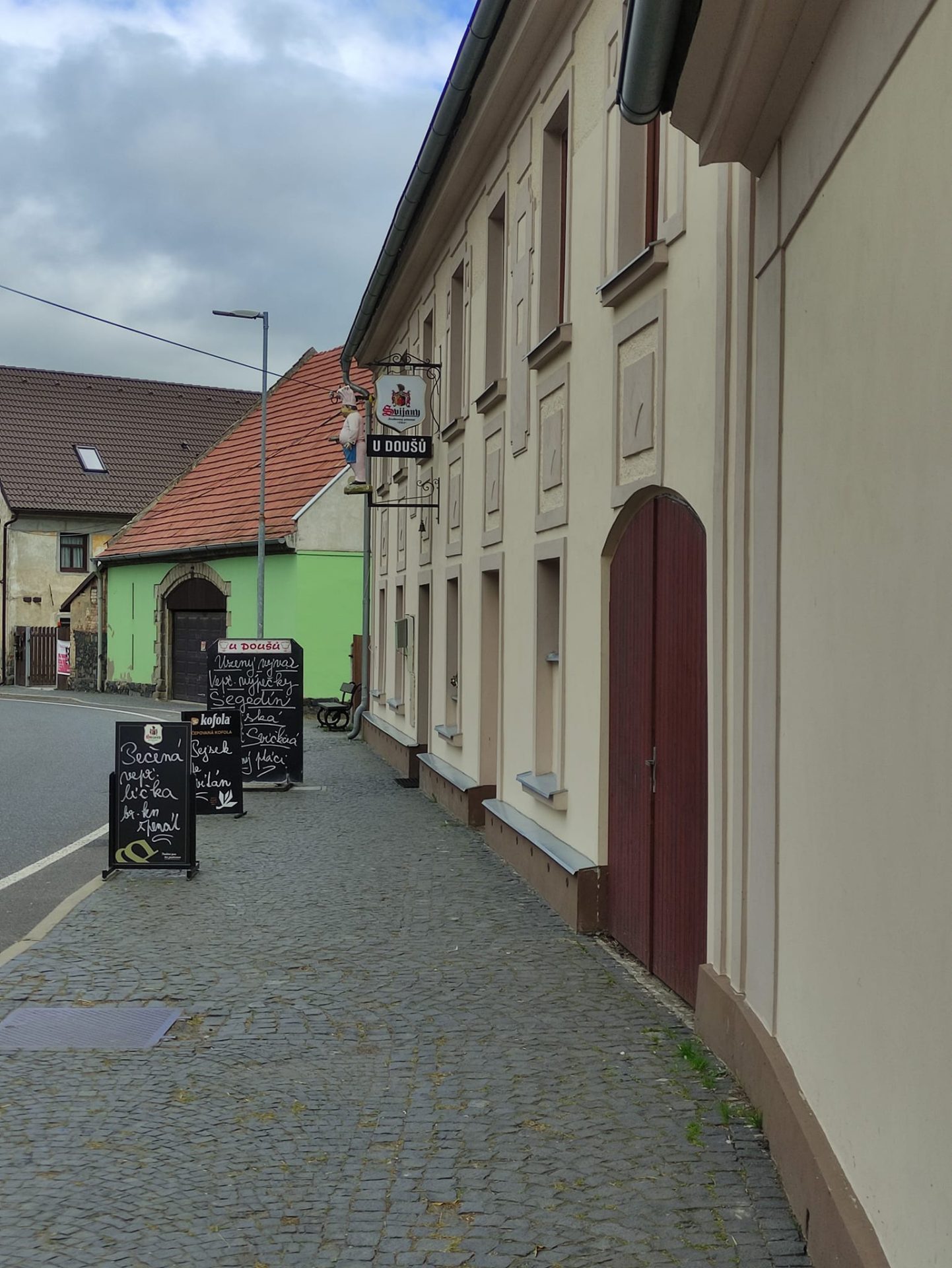 Ulice s Restaurací U Doušů a nabídkovými tabulemi